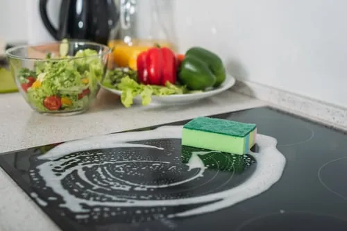 Kitchen cooktop being scrubbed during a routine home clean